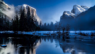 body-of-water-beside-trees-by-snowfield-near-mountains