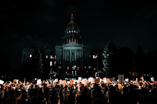 people-rallying-in-front-of-white-building-during-nightime