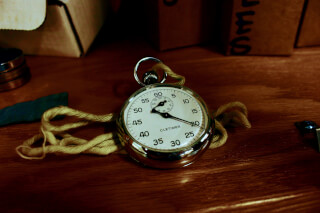 white-pocket-watch-with-gold-colored-frame-on-brown-wooden